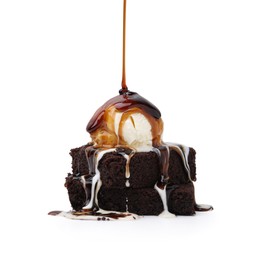 Photo of Pouring tasty caramel sauce onto ice cream and brownies isolated on white