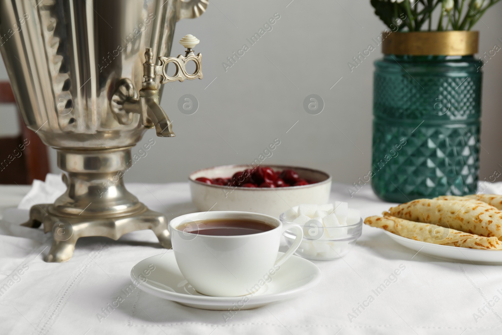 Photo of Vintage samovar, cup of hot drink and snacks served on table. Traditional Russian tea ceremony