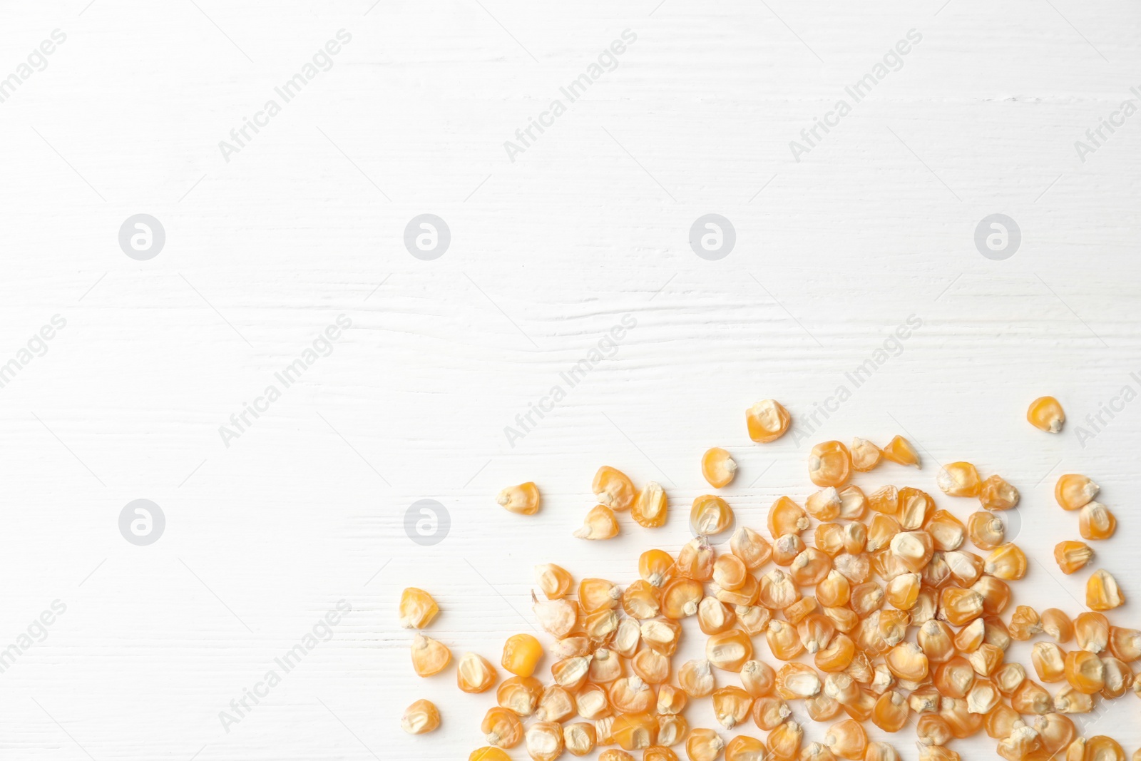 Photo of Raw dry corn seeds and space for text on white wooden background, flat lay. Vegetable planting