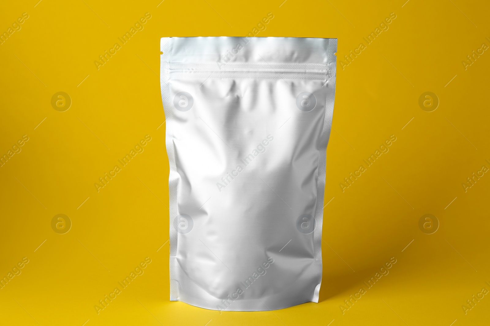 Photo of One blank foil package on yellow background