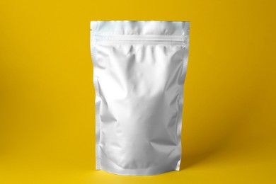 Photo of One blank foil package on yellow background