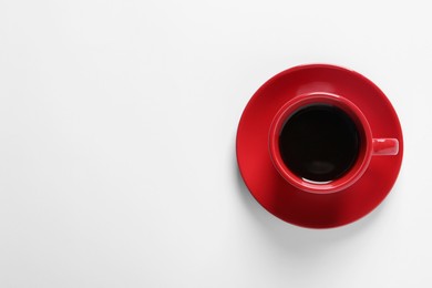 Red cup with aromatic coffee on white background, top view. Space for text