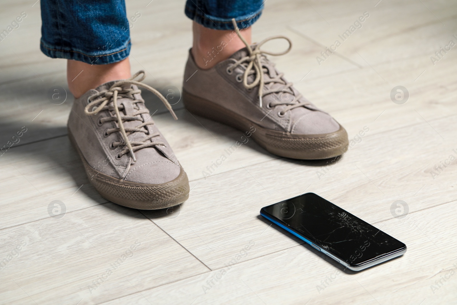 Photo of Woman near dropped smartphone on floor, closeup. Device repairing