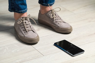 Woman near dropped smartphone on floor, closeup. Device repairing