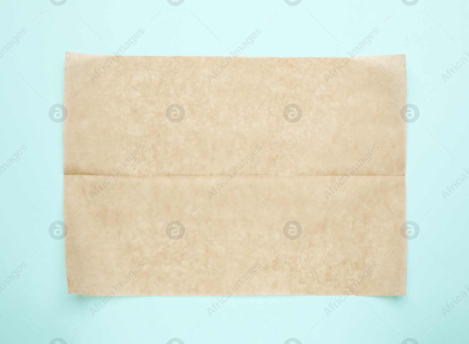 Photo of Sheet of brown baking paper on light blue background, top view