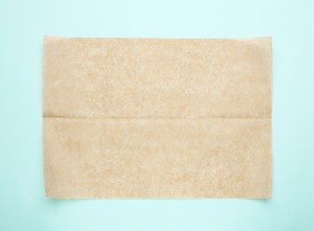 Photo of Sheet of brown baking paper on light blue background, top view