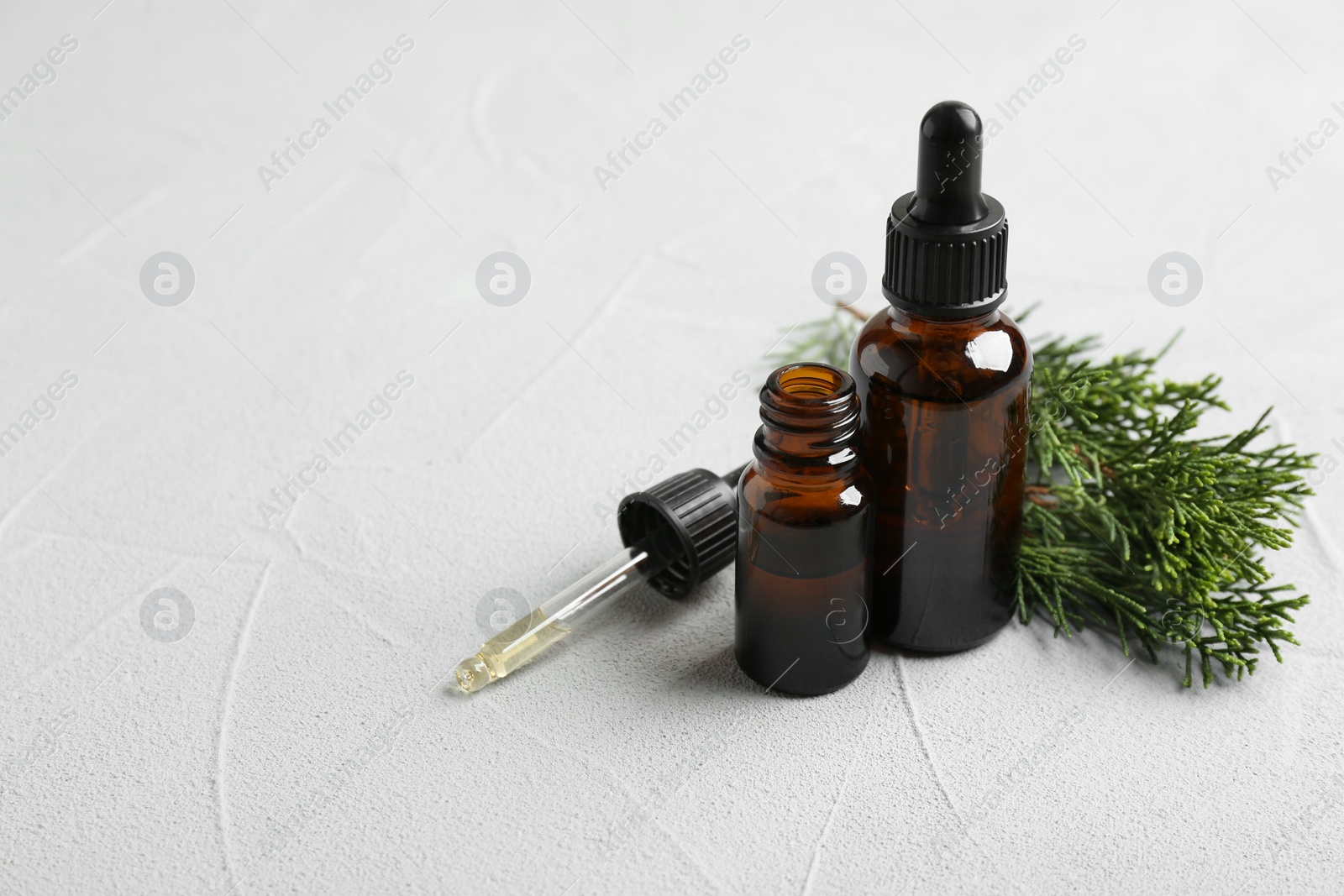 Photo of Composition with bottles of conifer essential oil on light background. Space for text