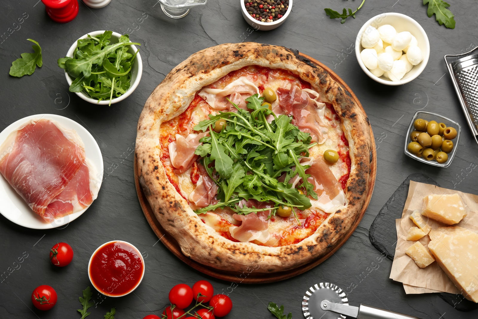 Photo of Tasty pizza with meat and arugula on black table, flat lay