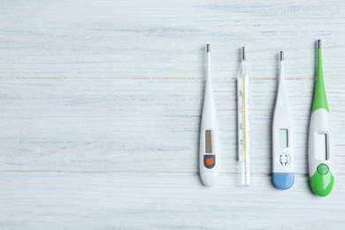 Different thermometers on white wooden background, flat lay. Space for text