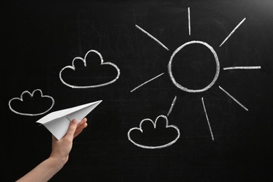 Photo of Woman holding paper plane near blackboard, closeup