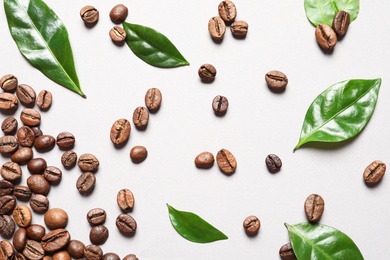 Photo of Fresh green coffee leaves and beans on light background, flat lay