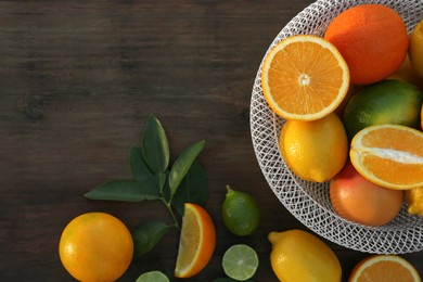 Photo of Different citrus fruits and leaves on wooden table, flat lay. Space for text