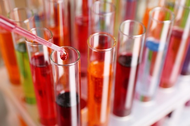 Photo of Dripping color liquid into test tube, closeup. Solution chemistry