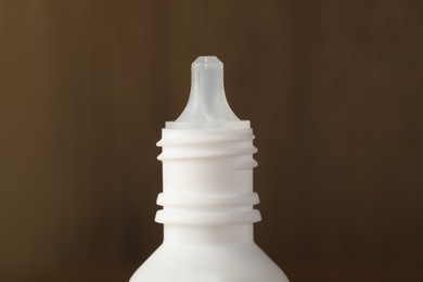 Photo of Bottle of nasal spray on brown background, closeup