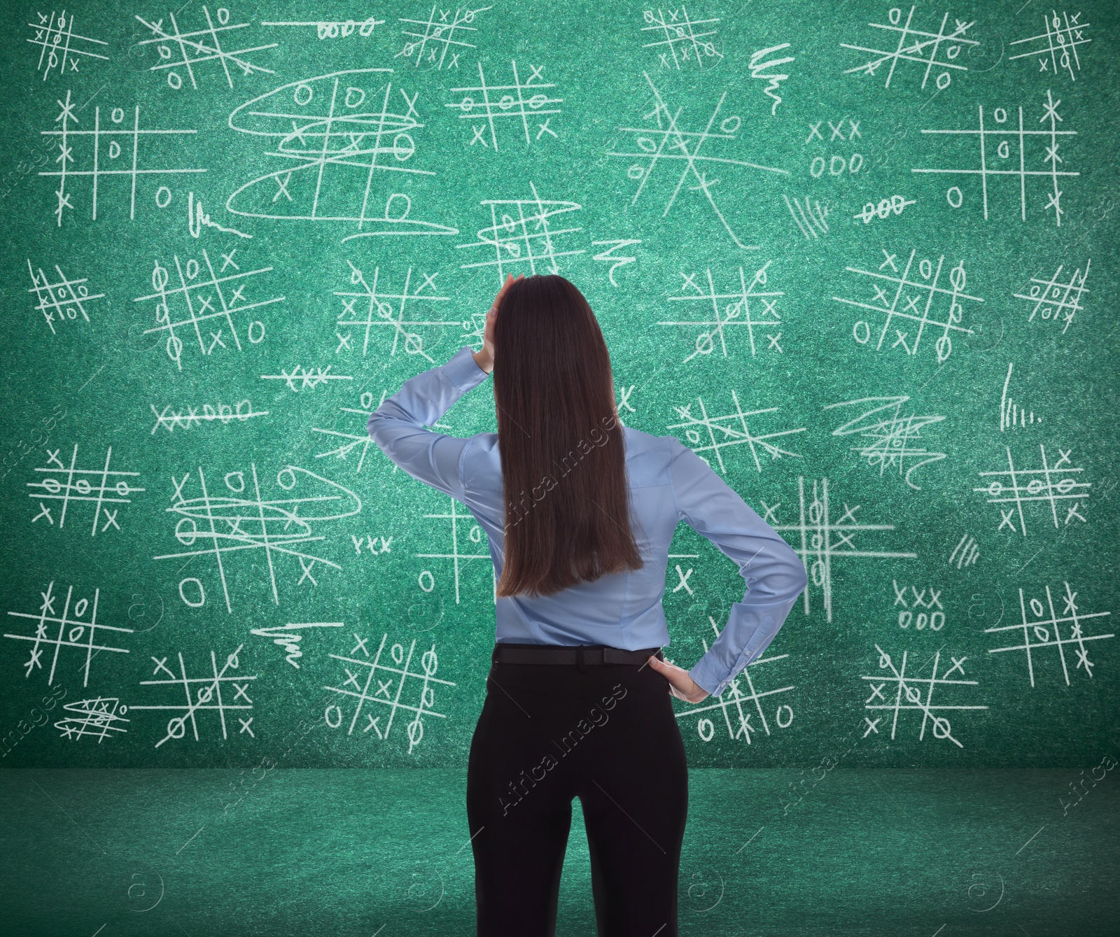 Image of Young businesswoman near green chalkboard with drawn tic tac toe game, back view