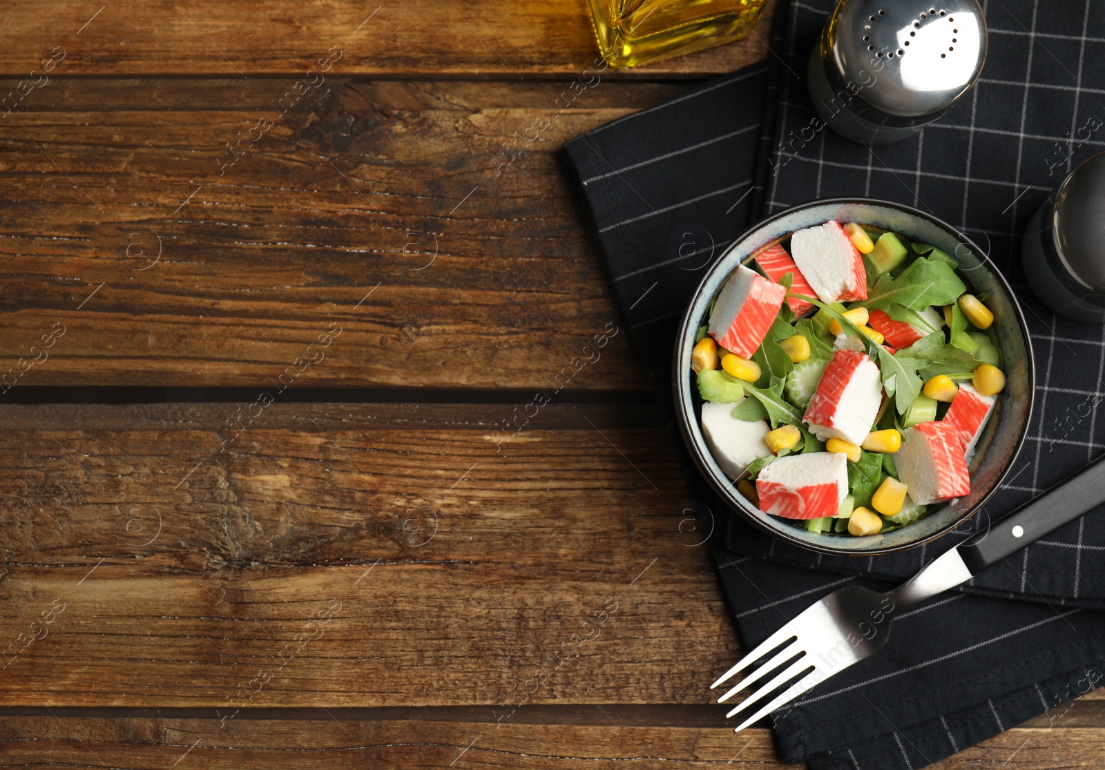 Photo of Tasty crab stick salad served on wooden table, flat lay. Space for text