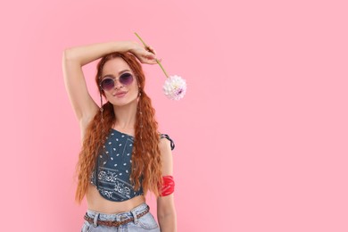 Photo of Stylish young hippie woman with dahlia flower on pink background, space for text