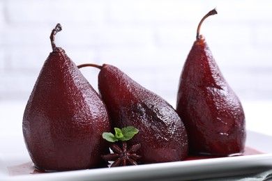 Photo of Tasty red wine poached pears with mint and anise on table, closeup