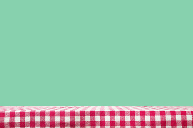 Checkered kitchen napkin on empty table against mint background. Space for design