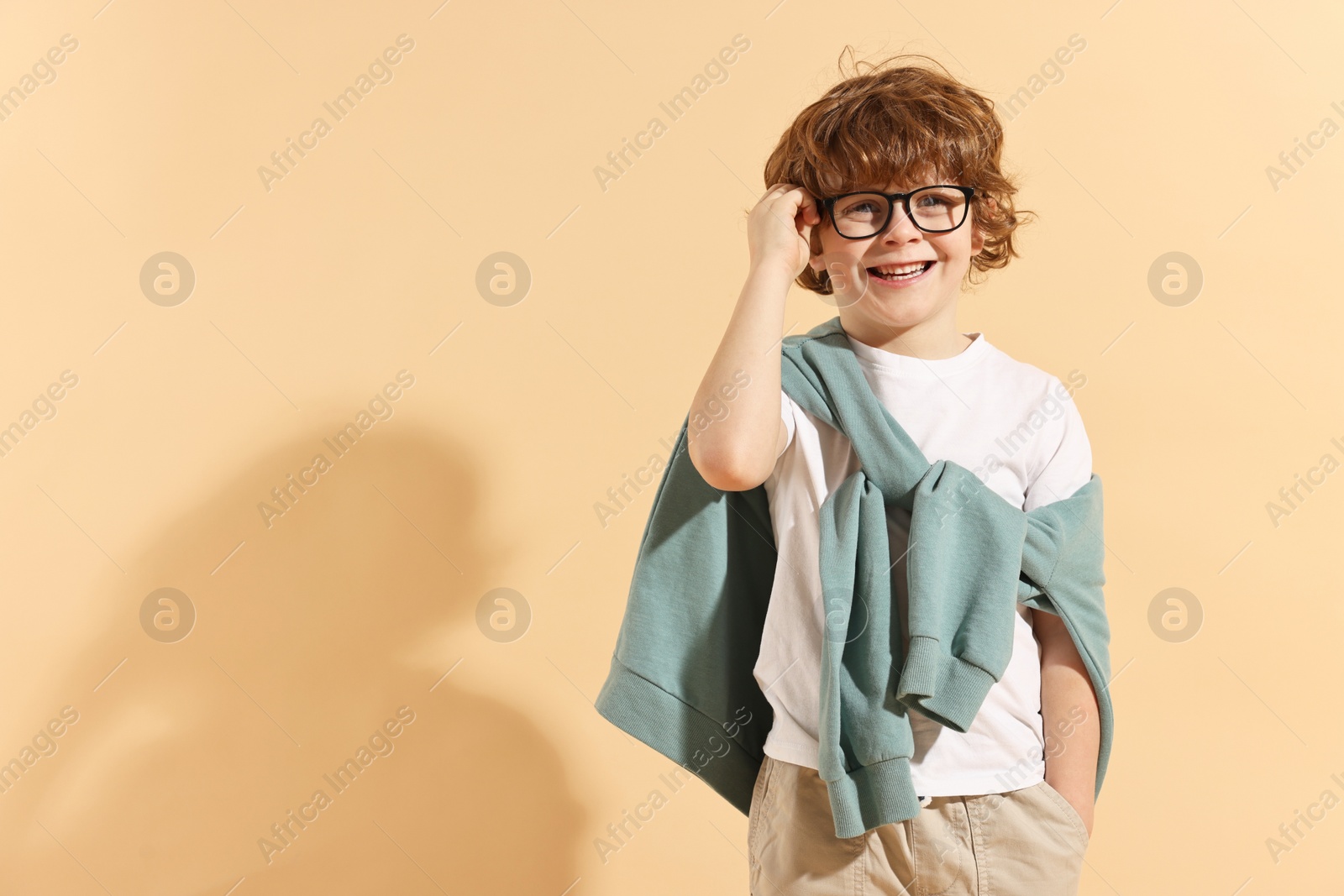 Photo of Fashion concept. Stylish boy on pale orange background. Space for text