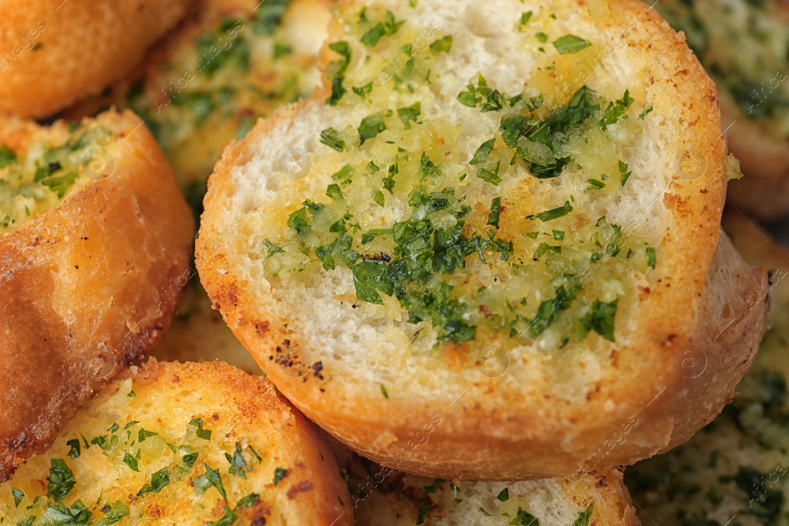 Photo of Slices of toasted bread with garlic and herbs as background, closeup