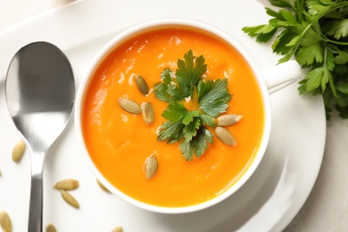 Bowl of tasty pumpkin soup on table, top view