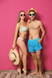 Photo of Happy young couple in beachwear against color wall