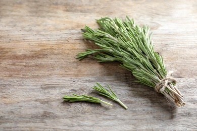 Photo of Fresh rosemary twigs tied with twine on wooden table