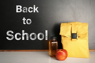 Healthy food for school child in lunch box on table near blackboard