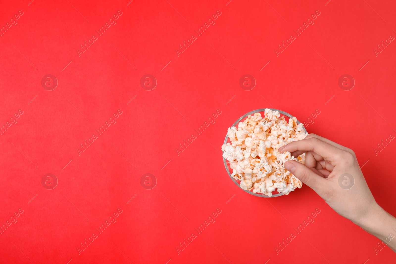 Photo of Woman eating popcorn on color background, top view. Space for text