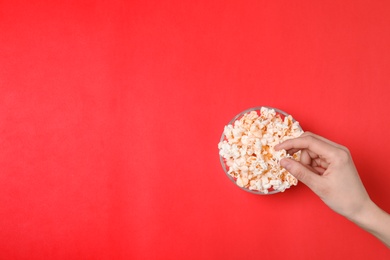 Woman eating popcorn on color background, top view. Space for text