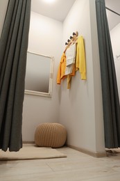 Photo of Dressing room with mirror in fashion store, low angle view. Stylish design