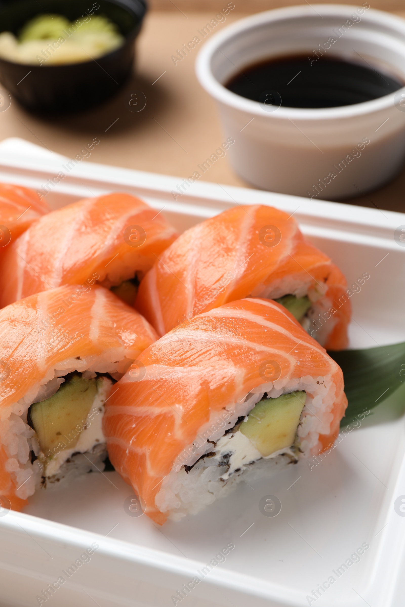 Photo of Food delivery. Delicious sushi rolls in plastic container, closeup