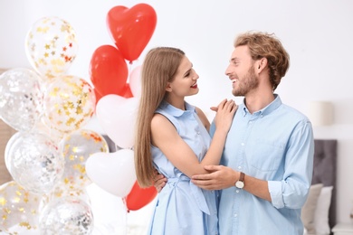 Young couple with air balloons in bedroom. Celebration of Saint Valentine's Day