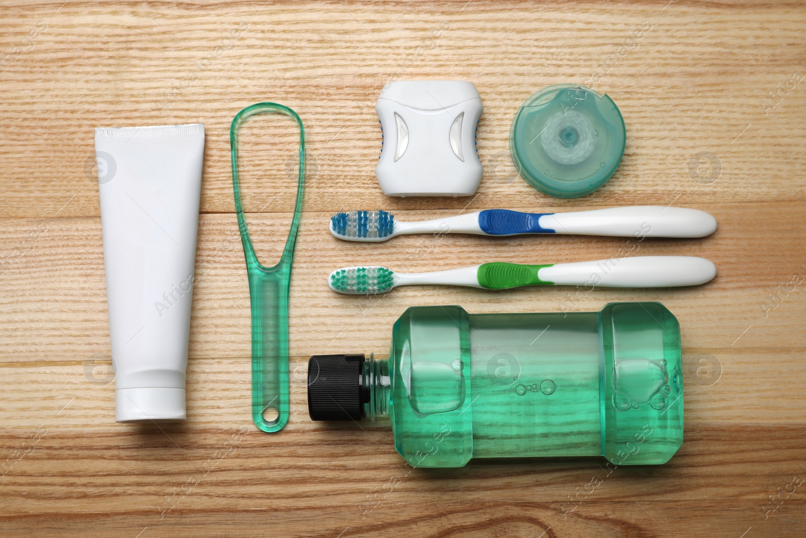 Photo of Flat lay composition with tongue cleaner and teeth care products on wooden table