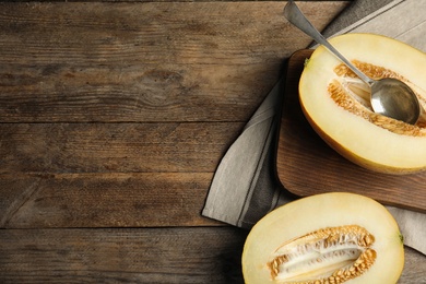 Photo of Cut ripe melon and spoon on wooden table, flat lay. Space for text