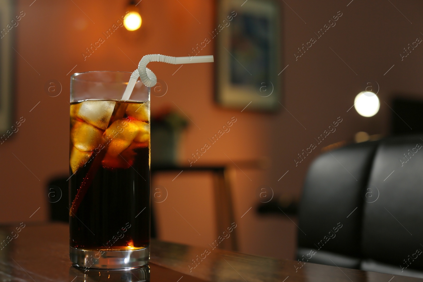 Photo of Glass of cold cola on table in dark room. Space for text