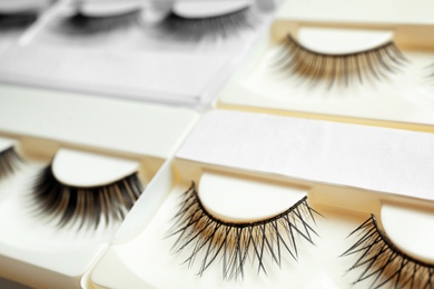 Set with different false eyelashes in packs as background, closeup