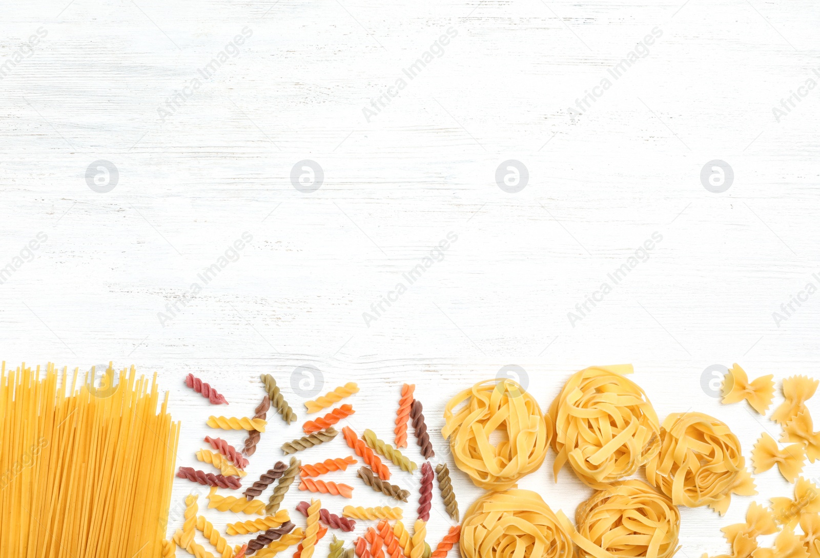 Photo of Beautiful composition with different raw pasta on wooden background, top view