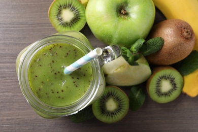 Photo of Delicious kiwi smoothie and ingredients on wooden table, flat lay