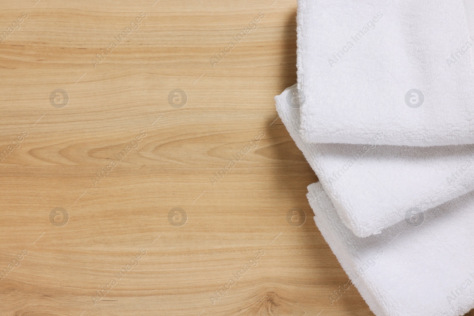 Photo of Soft folded terry towels on wooden table, top view. Space for text