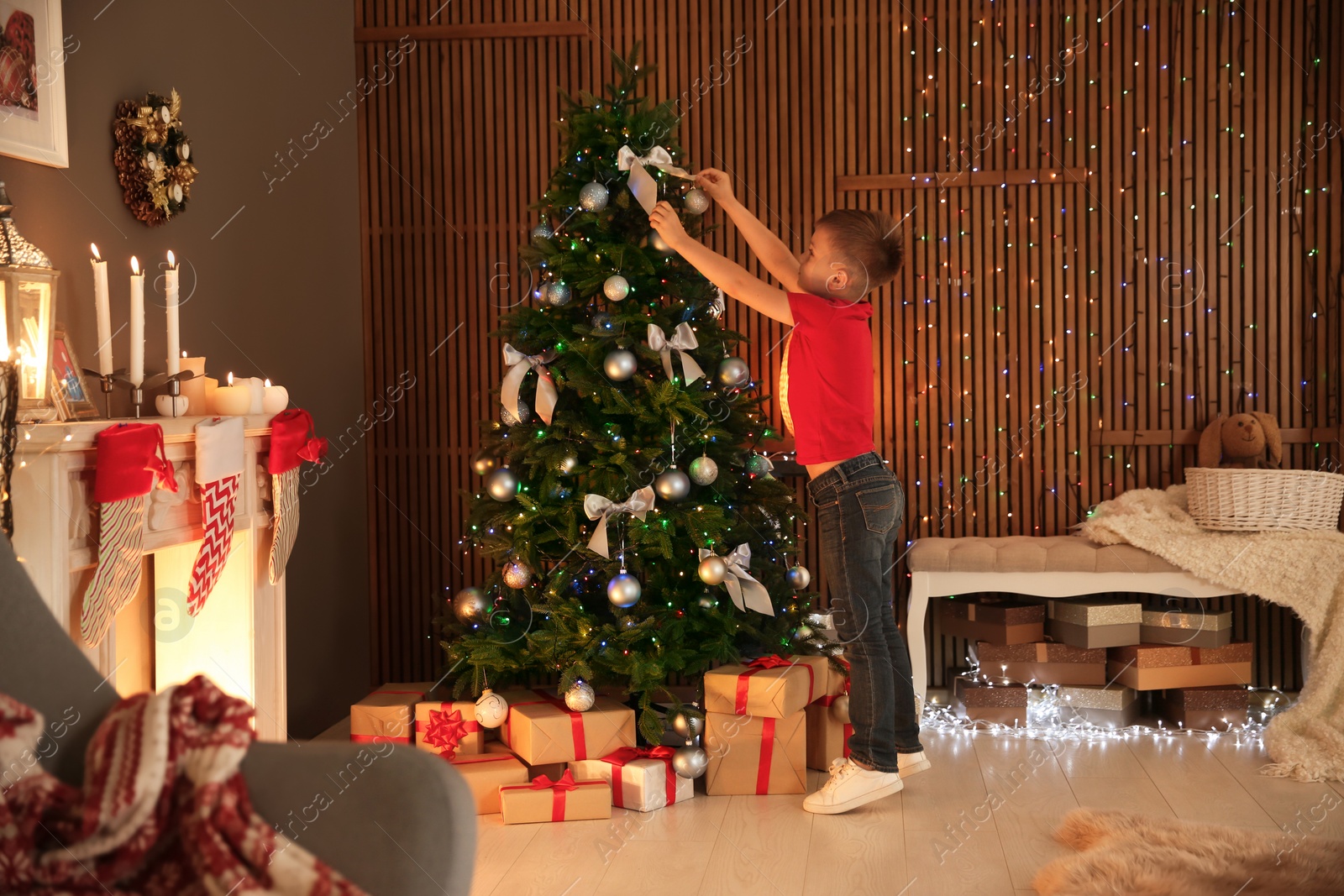 Photo of Cute little child decorating Christmas tree at home