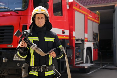 Portrait of firefighter in uniform with high pressure water jet near fire truck outdoors