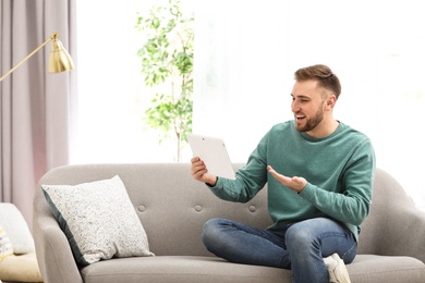 Young man using video chat on tablet in living room