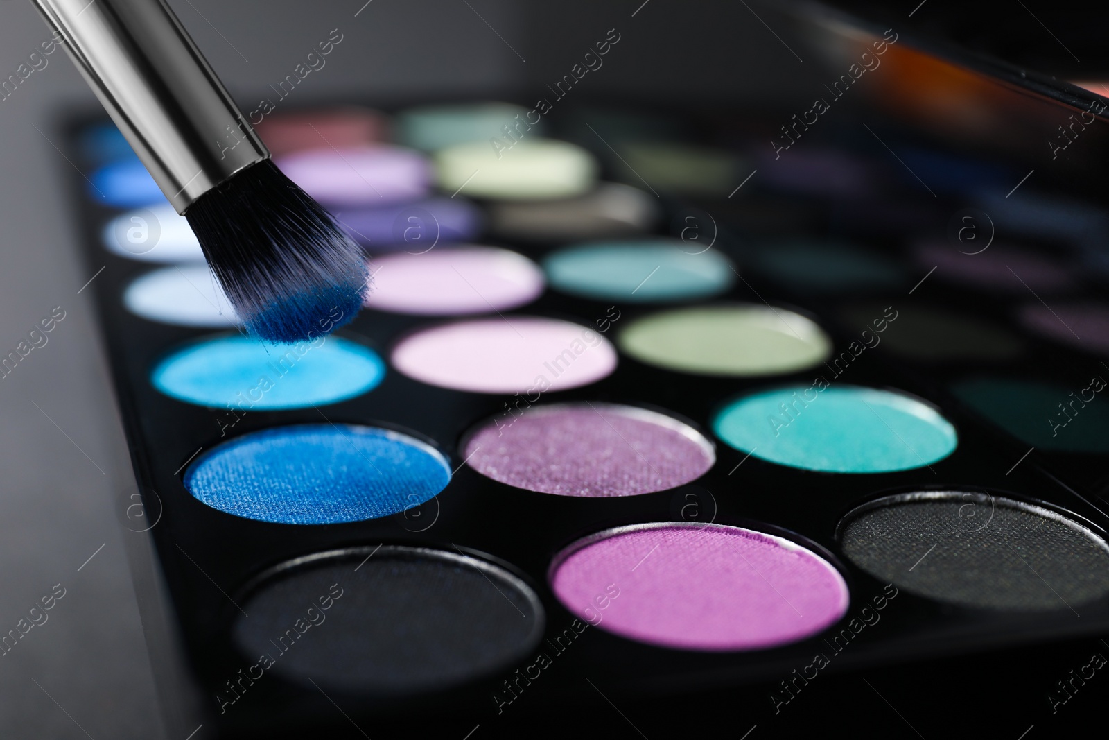 Photo of Colorful eyeshadow palette with brush, closeup view