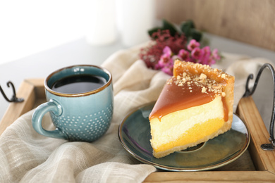 Photo of Cup of tea and delicious cheesecake on wooden tray, closeup
