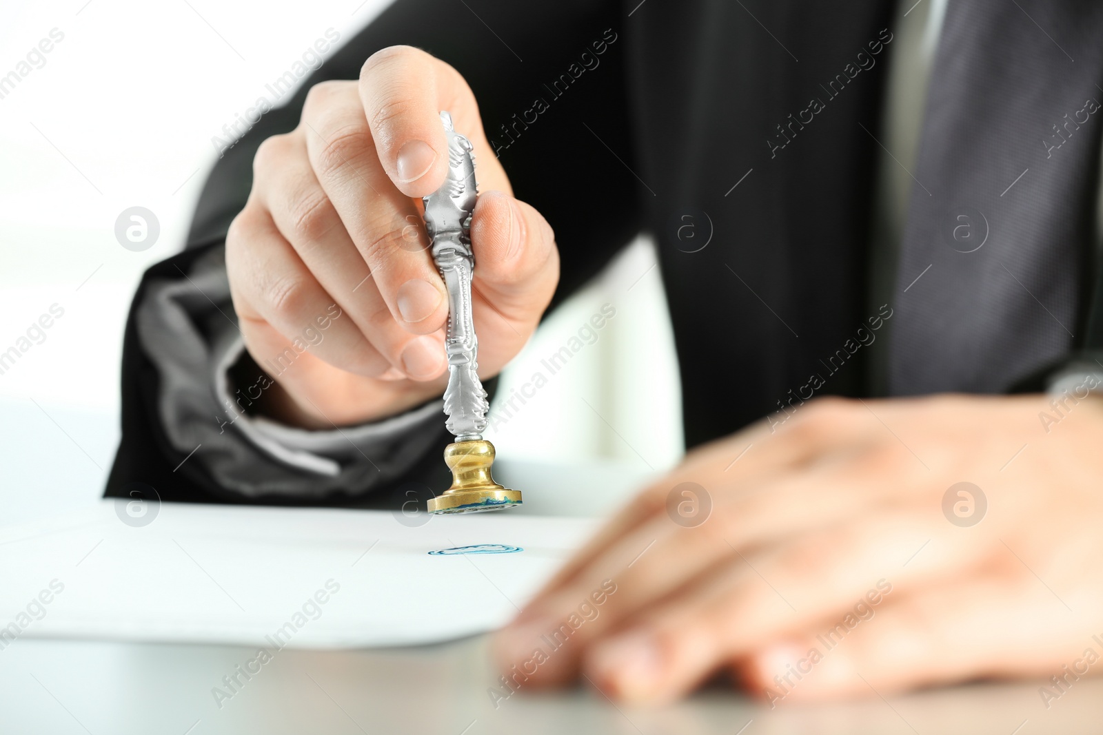 Photo of Male notary stamping document at table, closeup