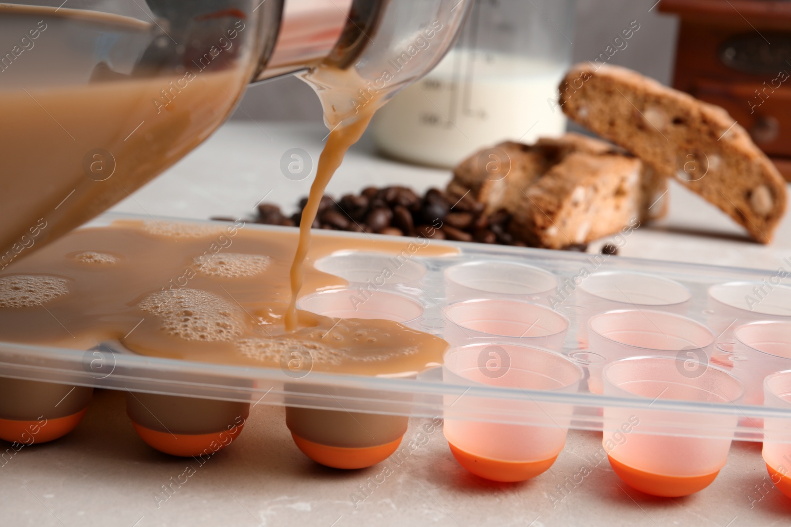 Photo of Pouring coffee drink into ice cube tray on table, closeup
