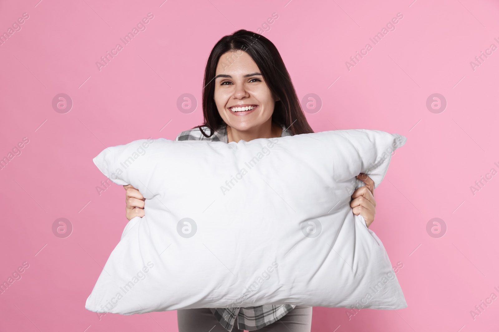 Photo of Happy young woman with soft pillow on pink background