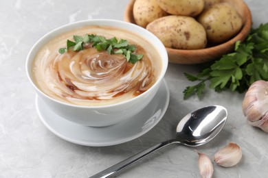 Photo of Delicious cream soup with soy sauce and parsley served on grey marble table